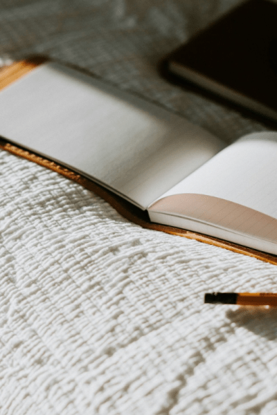 An open notebook and pencil on a bed